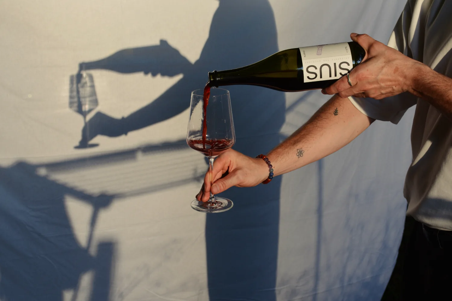 Das Getränk SIUS PURPUR wird vor einem weißen Hintergrund in ein Weinglas geschenkt.